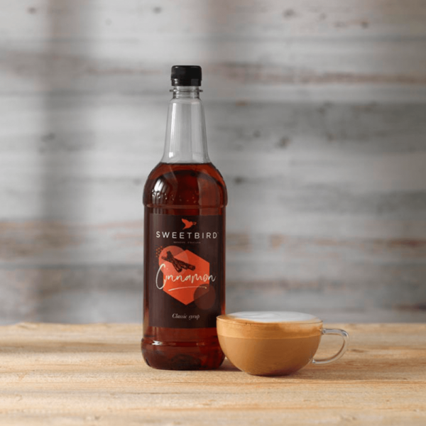 bottle of sweet bird cinnamon syrup with hot beverage beside