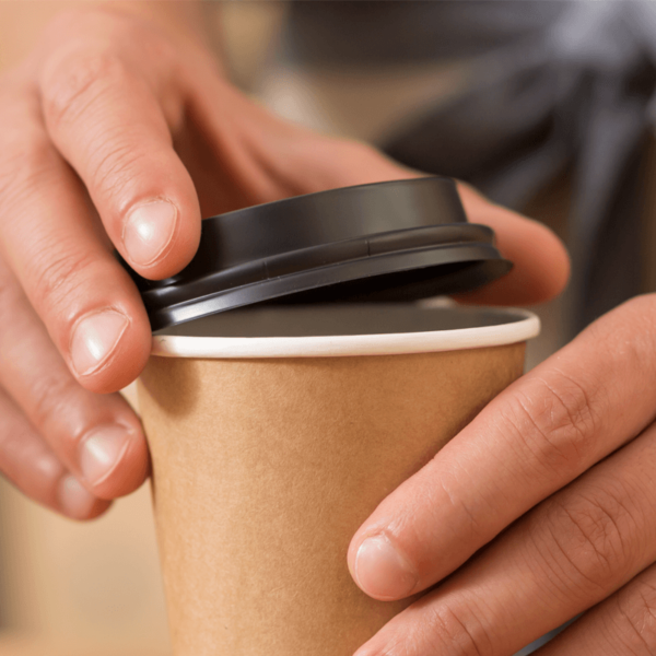 Person putting black plastic lid on paper drinks cup